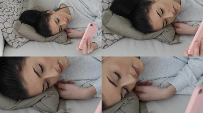 年轻女子躺在沙发上看手机的显示屏