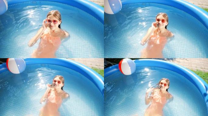 戴着太阳镜的快乐微笑女孩的俯视图躺在室外游泳池放松。暑假和假期快乐愉快的概念