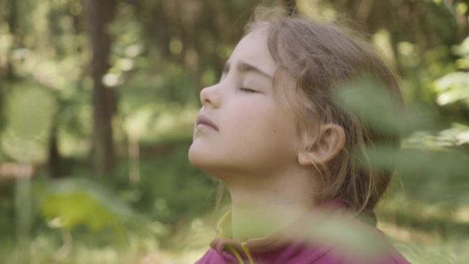 肖像儿童女孩呼出新鲜空气，深呼吸，减轻森林压力。梦幻般的平静轻松微笑的小女孩呼吸新鲜空气自然，宁静的