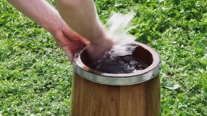 男人用手和清水冲洗一个新的橡木浴缸