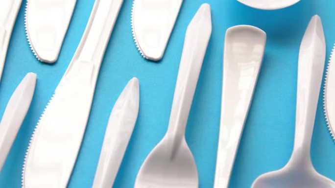 蓝色背景上的一次性白色塑料餐具。概念: 禁止一次性使用塑料。