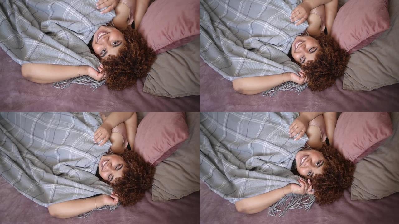 美丽的曲线加大码非洲黑人妇女非洲头发躺在床上，灰色格子毯子舒适的卧室室内设计。身体缺陷、身体接受、身