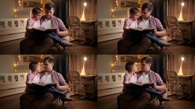 微笑的小男孩听睡前故事他的父亲晚上正在给他读。儿童教育和家庭晚上在一起的概念