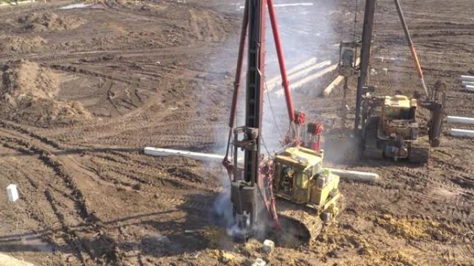在施工现场开挖，带有隆隆声和烟雾的柴油打桩机将桩深入地面，以确保未来结构的基础强度