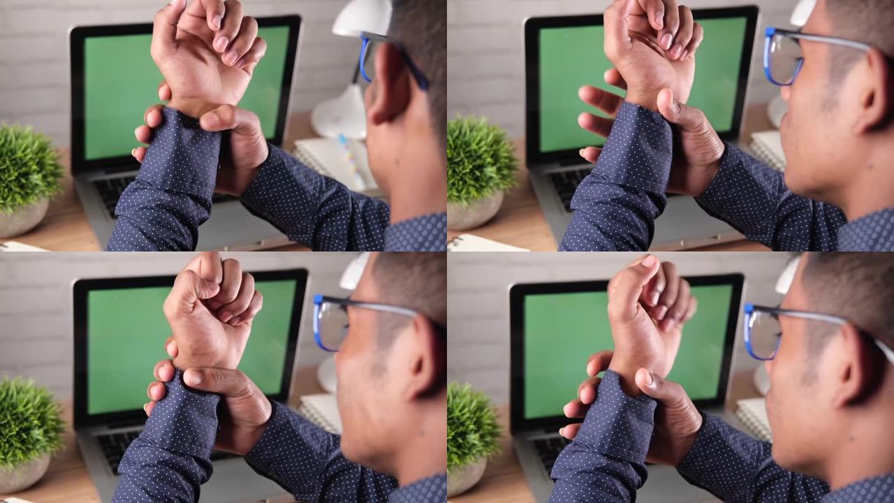 男子在笔记本电脑上工作时手握疼痛
