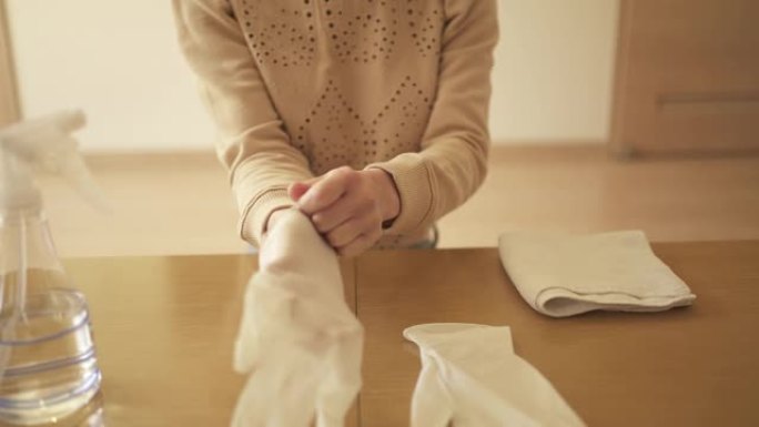 中年妇女戴着丁腈手套用酒精对客厅进行消毒。