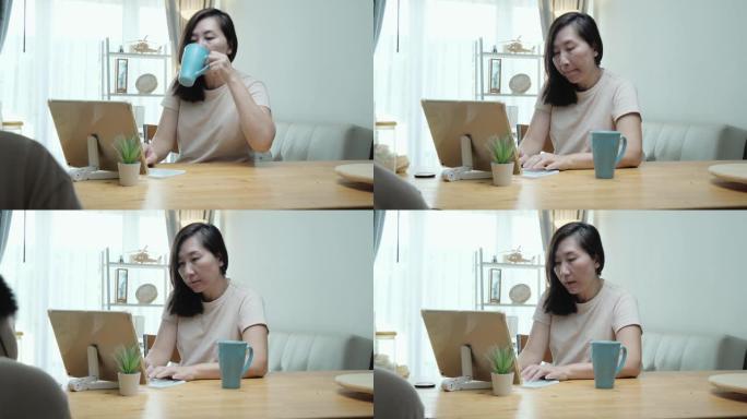 亚洲成年女性在新型冠状病毒肺炎期间在家餐桌上使用数字平板电脑，检疫生活方式概念。