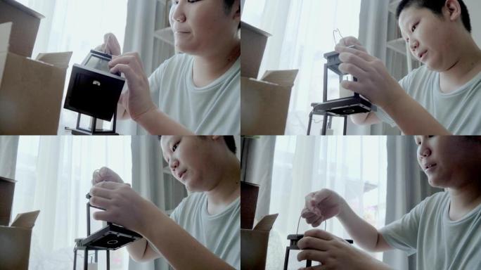 亚洲男孩从泡泡纸上拆开灯笼，这是从家里网上购物购买的，生活方式概念。