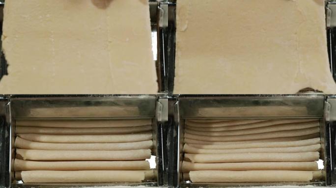 传统的意大利自制面食是在切面团的机器上制作的。从面条机出来的新鲜意大利面，特写镜头。厨师使用意大利面