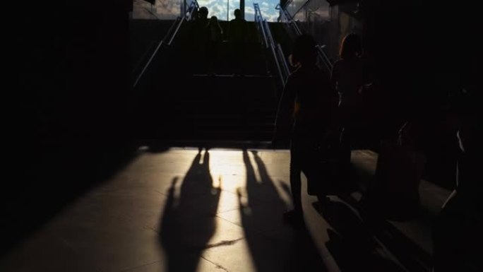 人们穿过地铁地下通道susnet楼梯附近的黑暗地下通道。剪影。通往地铁的走廊。旅游和城市生活概念，抽