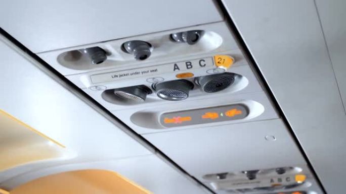 近距离拍摄空调通风口、单独的灯和飞机天花板上系紧安全带的标志的4k镜头