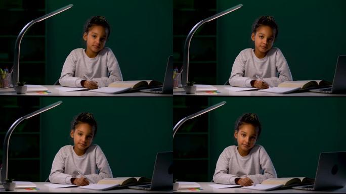 女孩若有所思地看着镜头，从手中松开了笔。一个女孩在夜灯的灯光下坐在桌子旁做作业。特写。慢动作就绪59