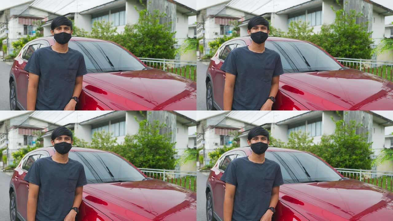 电影拍摄的快乐亚洲男子的肖像在车前，在面具脸后面微笑。