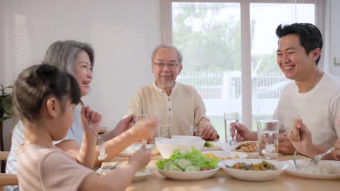 亚洲幸福大家庭一起花时间在餐桌上吃午饭。小女儿喜欢和父亲、母亲和祖父母一起吃饭。多代关系和房屋活动