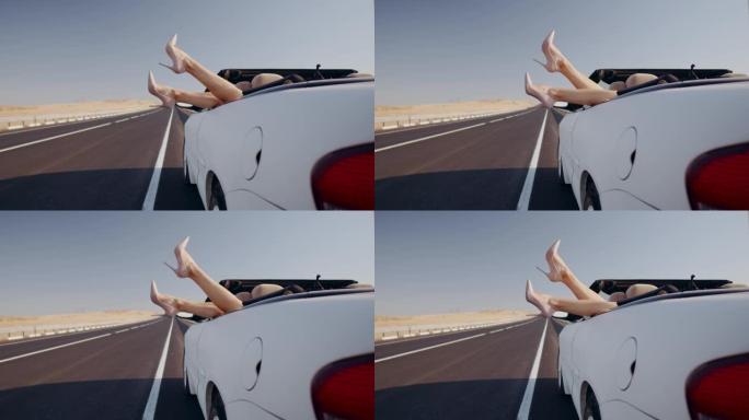 女人躺在后座的敞篷车上，在空荡荡的道路背景下，摆动的双腿特写镜头。在空荡荡的高速公路上，用白色敞篷车