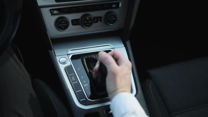 驾驶员的adm包括模式驱动上的变速杆自动变速器的豪华车内饰件。穿着西装的商人手控制变速杆变速器