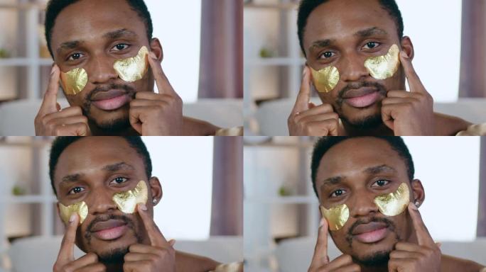心情愉快现代年轻的黑皮肤男人与金色胶原蛋白眼罩合影，面部护理概念