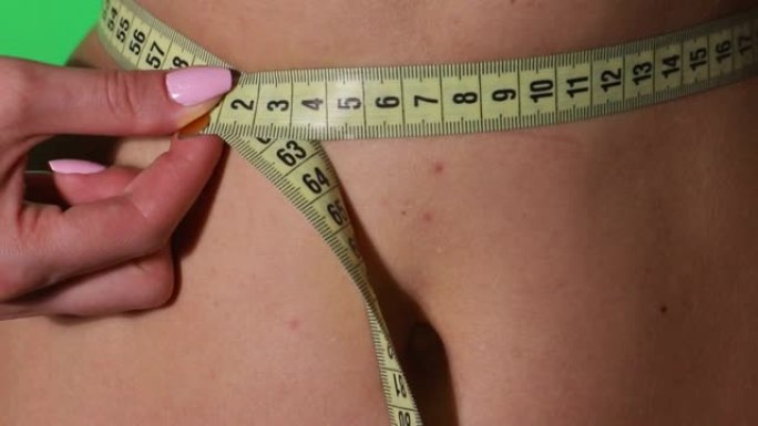 女孩测量腰部，保护良好的营养和健康的生活方式。