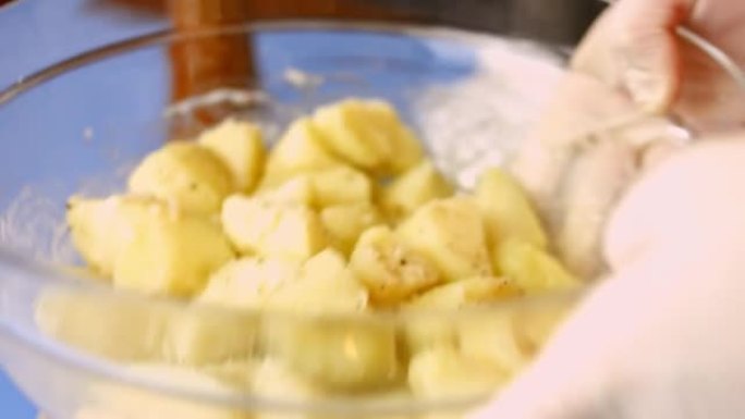摇动玻璃碗，将煮熟的金色土豆与盐和黑胡椒混合。烹饪完美烤箱烤土豆的过程
