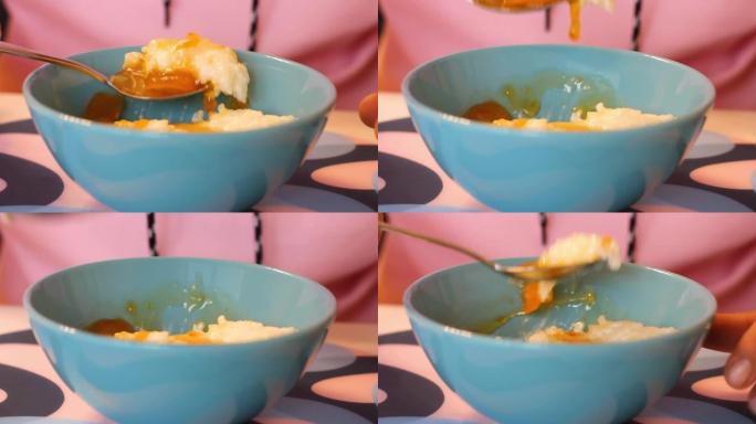 一个人用勺子从盘子里吃杏酱米粥。早餐