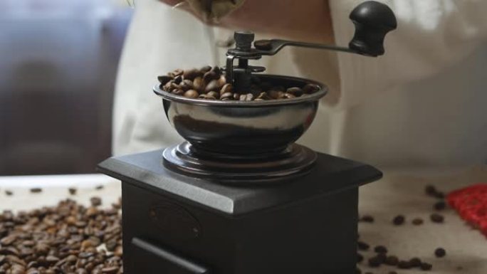 早晨，一个穿着白大褂的男人将咖啡豆从布袋中倒入复古的咖啡研磨机中。多莉开枪。手工制作的美式早晨能量提
