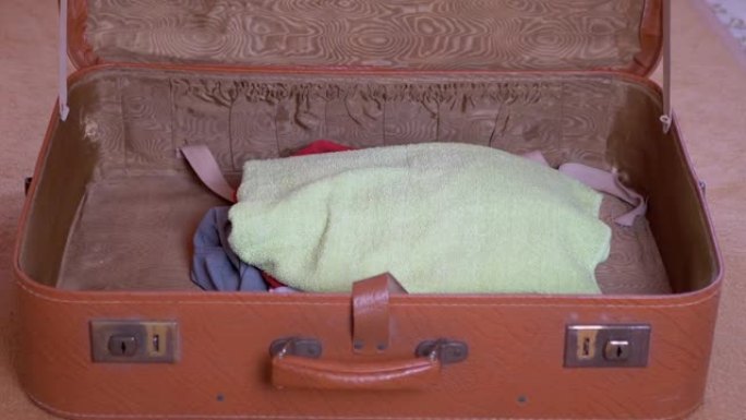 一大堆东西和一个面具一起扔在一个开着的旧手提箱里。缩放