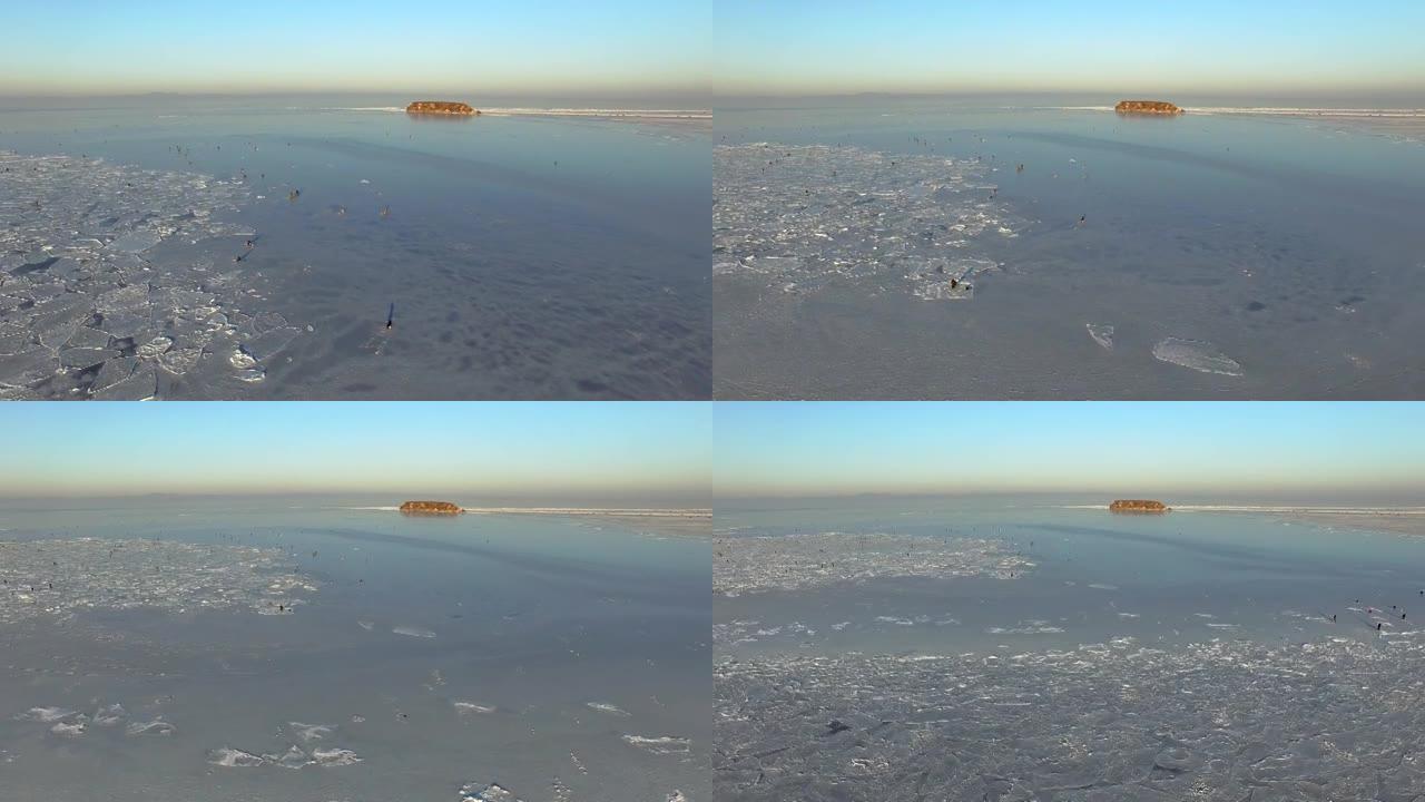 无人驾驶飞机在冰雪覆盖的冬季海中观察一个多岩石的岛屿