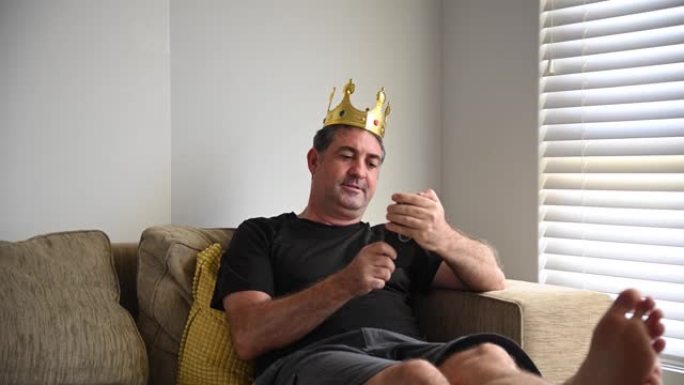 懒惰成熟的成年男子在家庭客厅表现得像国王