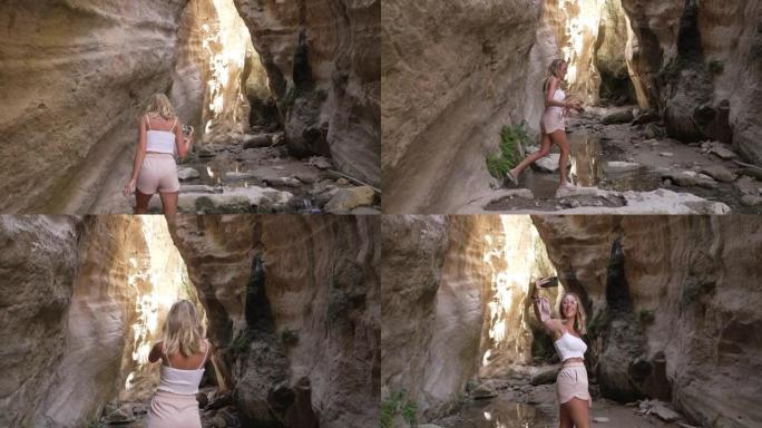 迷人的年轻女子在假期期间访问Avakas Gorge，并在手机上自拍，以便对它有记忆