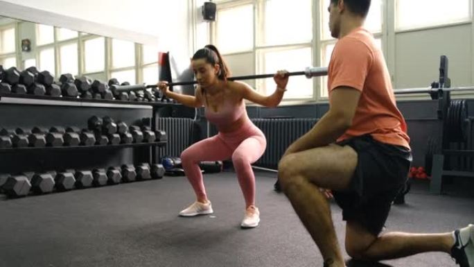 开朗的女运动员与她的私人教练在健身房训练