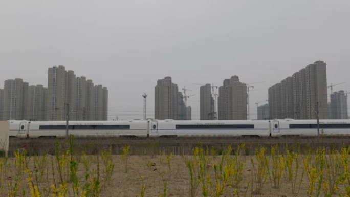 在春天的田野里，火车穿过城市建筑。