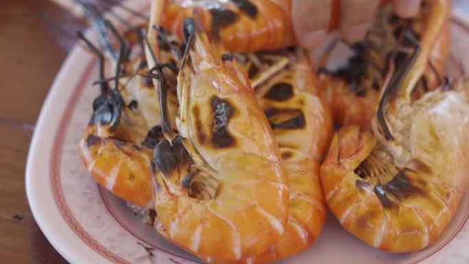 特写并有选择地聚焦4k视频，其中有许多橙色的大虾烤虾作为海鲜在盘子中食用，并看到人们在餐厅采摘美味的
