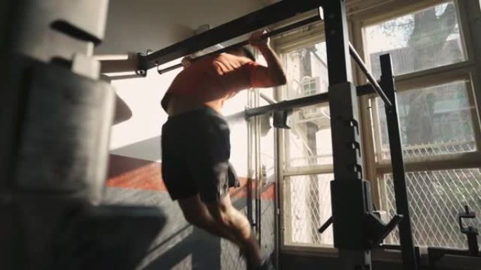 一个年轻的运动型男子在健身房做蝴蝶引体向上