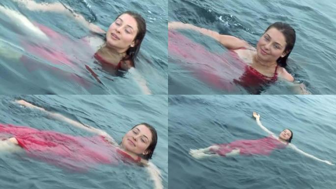 在红海的水中穿着红色连衣裙的自由潜水员模型。