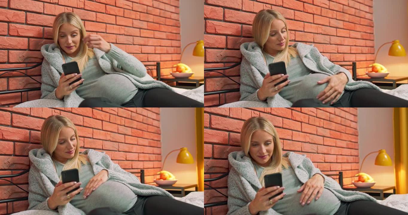快乐的孕妇年轻女子通过使用智能手机聊天并发短信给丈夫或家人，她的婴儿或胎儿身体健康，身体强壮，几个月
