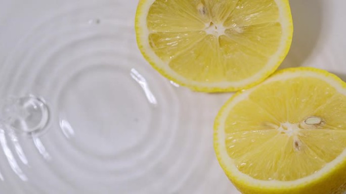 柠檬一半，躺在水中，水滴落下，发散的圆圈。健康饮食的天然柑橘类水果柠檬