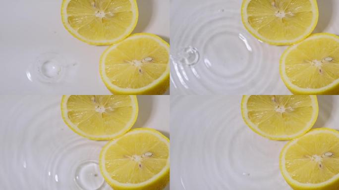 柠檬一半，躺在水中，水滴落下，发散的圆圈。健康饮食的天然柑橘类水果柠檬