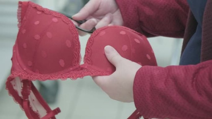 孕妇在服装店选择一个大的红色胸罩。双手特写镜头