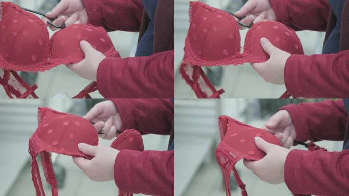 孕妇在服装店选择一个大的红色胸罩。双手特写镜头