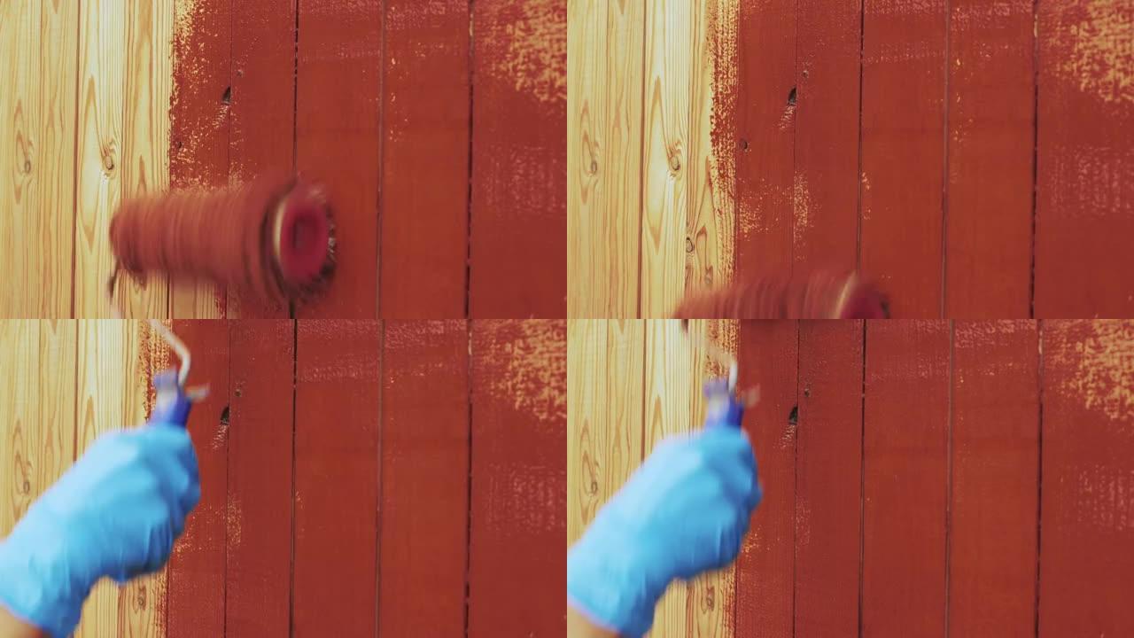 画家用棕色或红色醇酸涂料在木板条的墙壁或栅栏上作画。