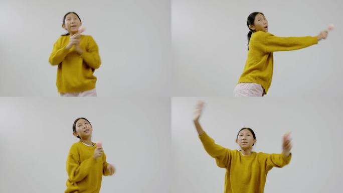 快乐的亚洲女孩穿着黄色毛衣与马拉卡在灰色背景上跳舞，生活方式理念。