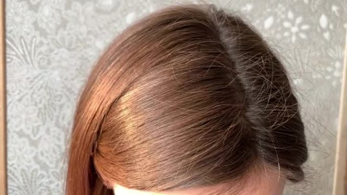 一个女人的头，有一头白发，由于检疫而长出了根。女人头上的棕色头发特写4K