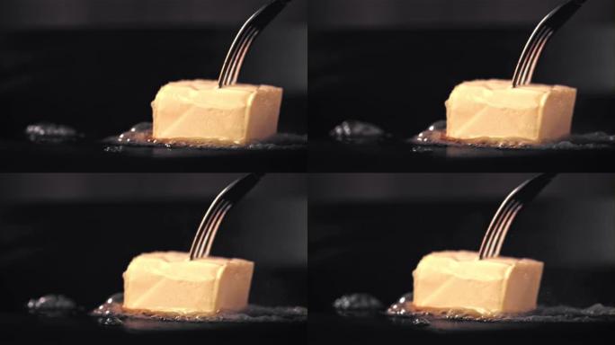 超级慢动作一块带叉子的黄油在煎锅中融化。以1000 fps的高速相机拍摄。