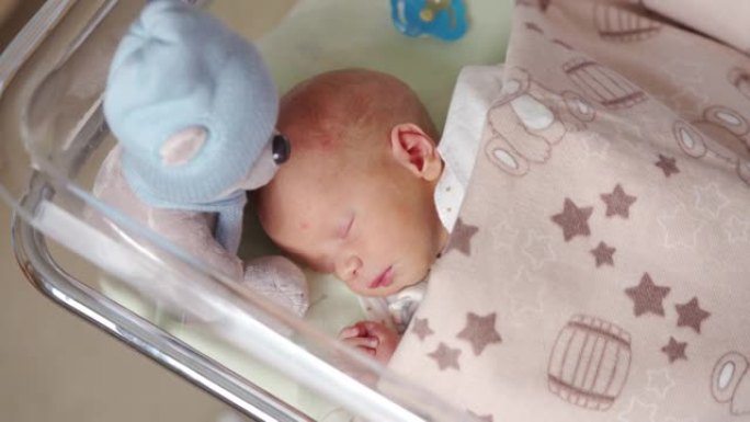 新生儿男婴躺在妇产医院的婴儿床里，婴儿正在睡觉