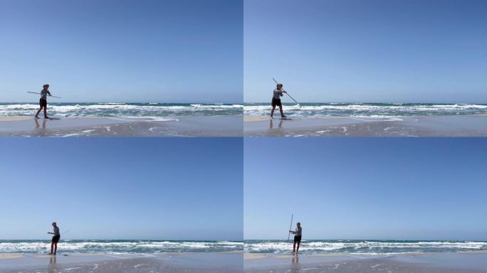少年少年武术在沙滩上用竹竿练习训练。活跃的人4k概念镜头。