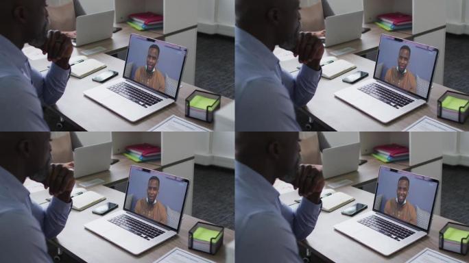 非裔美国高级男子在笔记本电脑上与办公室的男性同事进行视频通话