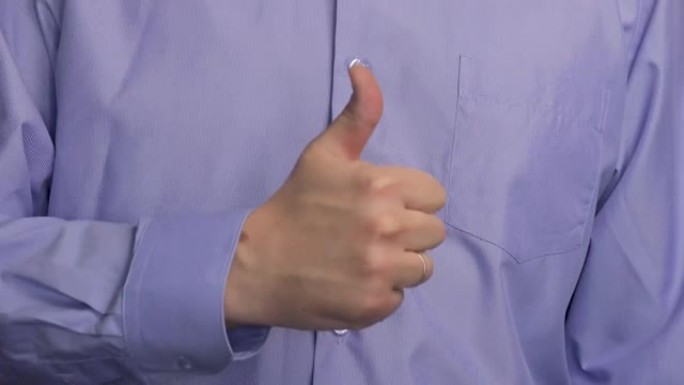 这个人竖起大拇指。一个穿蓝色条纹衬衫的男人。