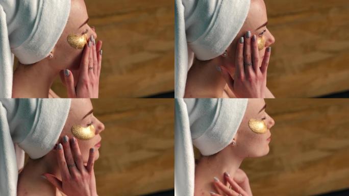 头戴毛巾的白人妇女正在涂抹水凝胶金色眼罩