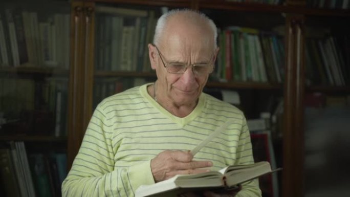 一位戴眼镜的老人手里拿着书签读圣经。