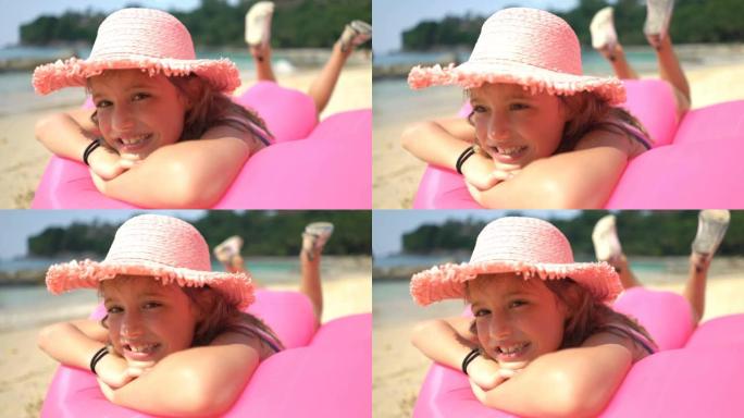 一个戴着粉红色草帽的小女孩躺在海滩上的充气沙发上。冠状病毒出口
